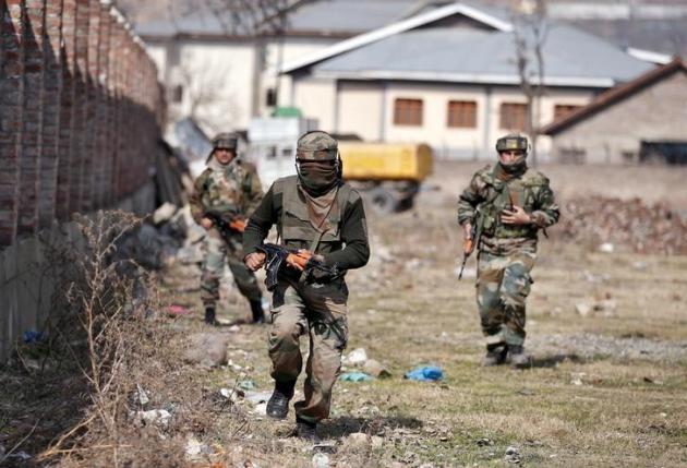 Indian army soldiers run to take their positions near the site of a gun battle between Indian security forces and militants on the outskirts of Srinagar