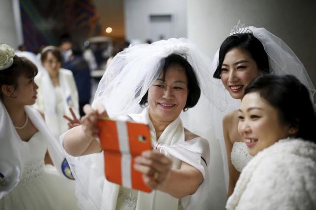 Brides take a selfie during a break in a mass wedding ceremony of the Unification Church at Cheongshim Peace World Centre in Gapyeong,