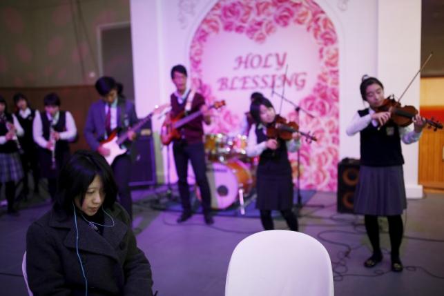 A high school band performs as a bride listens during an opening ceremony for an upcoming mass wedding ceremony of the Unification Church at Cheongshim Peace World Centre in Gapyeong