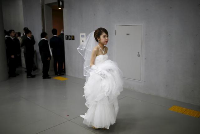 A bride walks past grooms queuing to go to the toilet during a break in a mass wedding ceremony of the Unification Church at Cheongshim Peace World Centre in Gapyeong