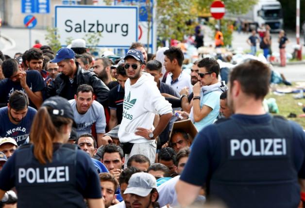 File photo of German police officers standing in front of migrants waiting to cross the border from Austria to Germany near Freilassing