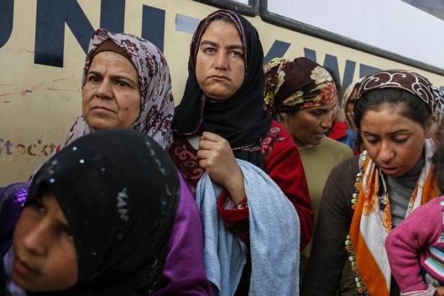 People queue to receive free food at a makeshift camp for migrants and refugees at the Greek-Macedonian border near the village of Idomeni