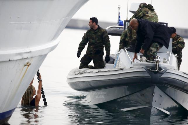 Greek Coast Guard officers in a speedboat approach activists hanging from the anchor's chain of a Turkish-flagged passenger boat carrying migrants to be returned to Turkey, in an attempt to prevent it from leaving the port of Mytilene, on island of Lesbos