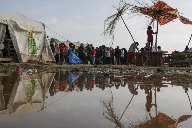 People queue to receive free food at a makeshift camp for migrants and refugees at the Greek-Macedonian border near the village of Idomeni