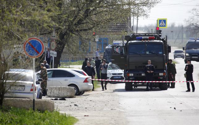 Interior Ministry officers, investigators and members of special services stand behind barrier tape in a settlement of the Novoselitsky district, where a local police station was recently attacked, in Stavropol region, southern Russia