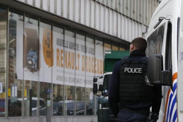 A Police officer stands in front of a car dearlership during a police operation after fugitive Mohamed Abrini was arrested in Anderlecht