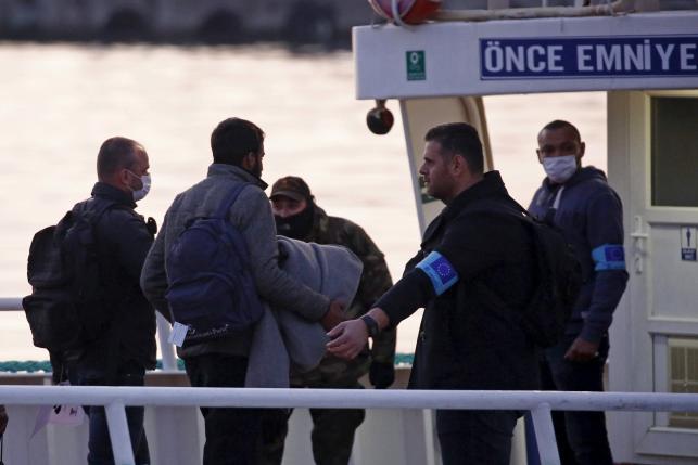 Frontex officers guide migrants boarding a Turkish-flagged passenger boat to be returned to Turkey, on the Greek island of Lesbos