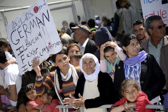 Migrants and refugees hold placards reading messages at Moria refugee camp near the port of Mytilene, on the Greek island of Lesbos