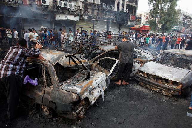 People inspect the site of a suicide car bomb in the Karrada shopping area, in Baghdad