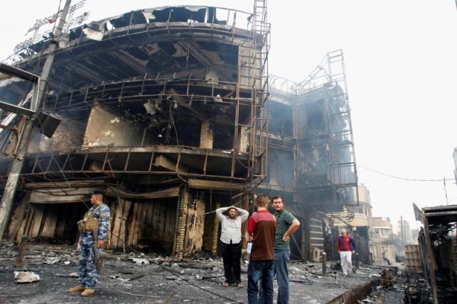People gather at the site of a suicide car bomb in the Karrada shopping area, in Baghdad, Iraq