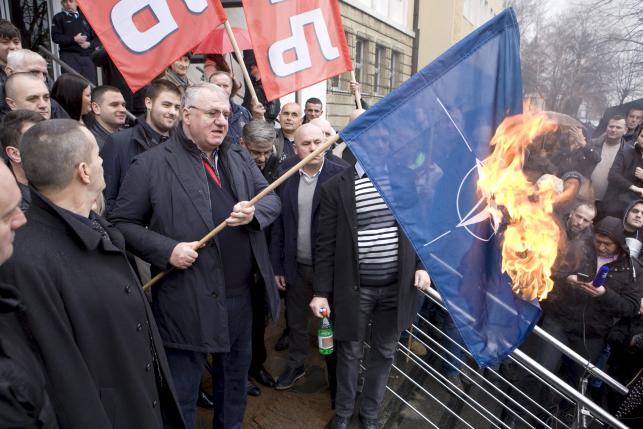 Serbian ultra-nationalist leader Seselj, surrounded by Radical Party supporters, burns NATO flag during a protest in front of the Special Court building in Belgrade