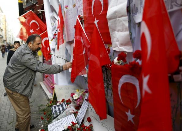 A man places carnations and a candle at the scene of a suicide bombing at Istiklal street, a major shopping and tourist district, in central Istanbul