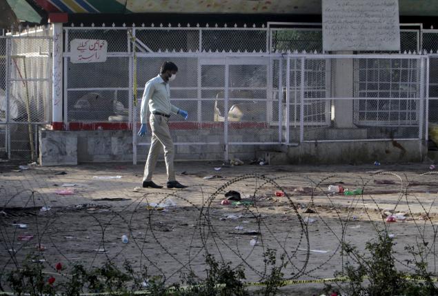 A forensic officer looks for evidence at the site of a blast that happened outside a public park on Sunday, in Lahore