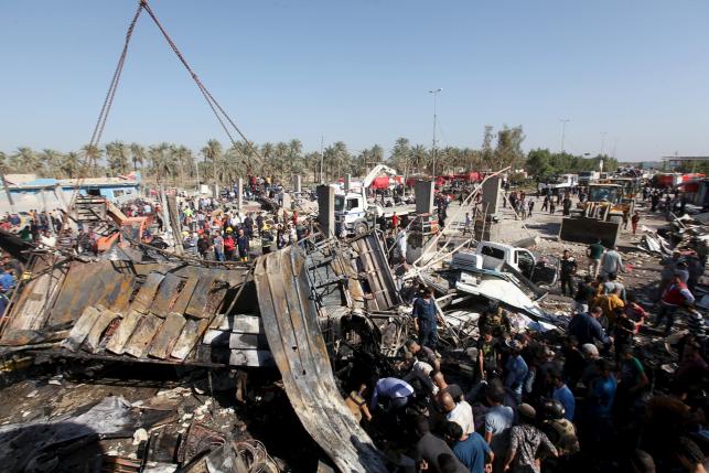 Residents gather at the site of a car bomb attack at a checkpoint in the city of Hilla
