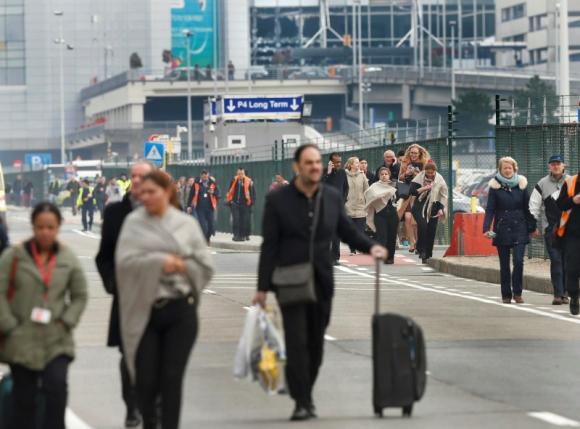 People leave the scene of explosions at Zaventem airport near Brussels, Belgium