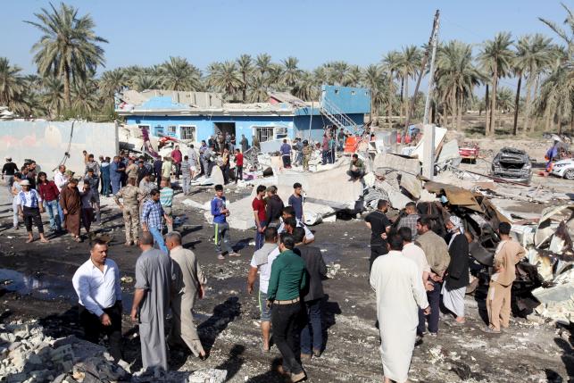 Residents gather at the site of a bomb attack at a checkpoint in the city of Hilla