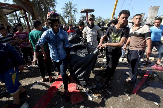 Residents carry the body of a victim of a bomb attack at a checkpoint in the city of Hilla