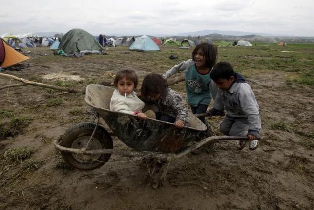 Children play in the mud with a cart at a makeshift camp for refugees and migrants at the Greek-Macedonian border, near the village of Idomeni