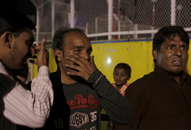 Men mourn the death of their relatives after a blast outside a public park in Lahore, Pakistan