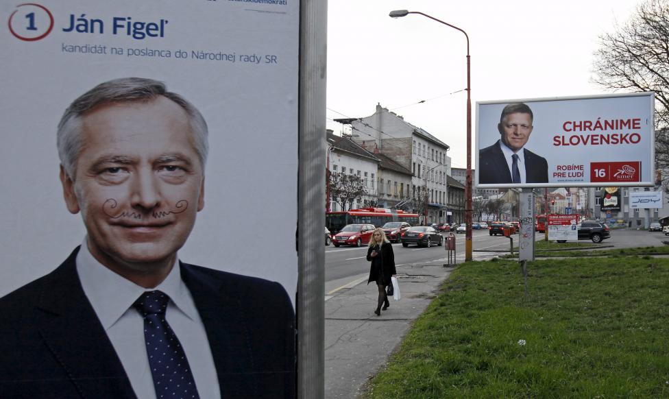 A woman walks past election posters showing candidates of Smer party Robert Fico and KDH party Jan Figel in Bratislava