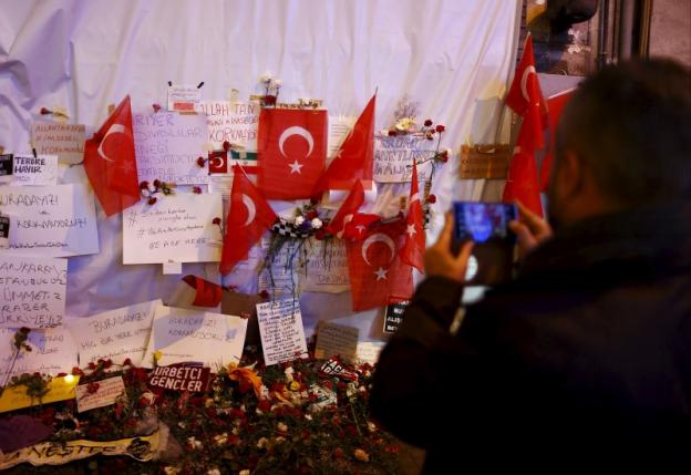 A man takes photos of tributes left at the scene of a suicide bombing at Istiklal street in Istanbul