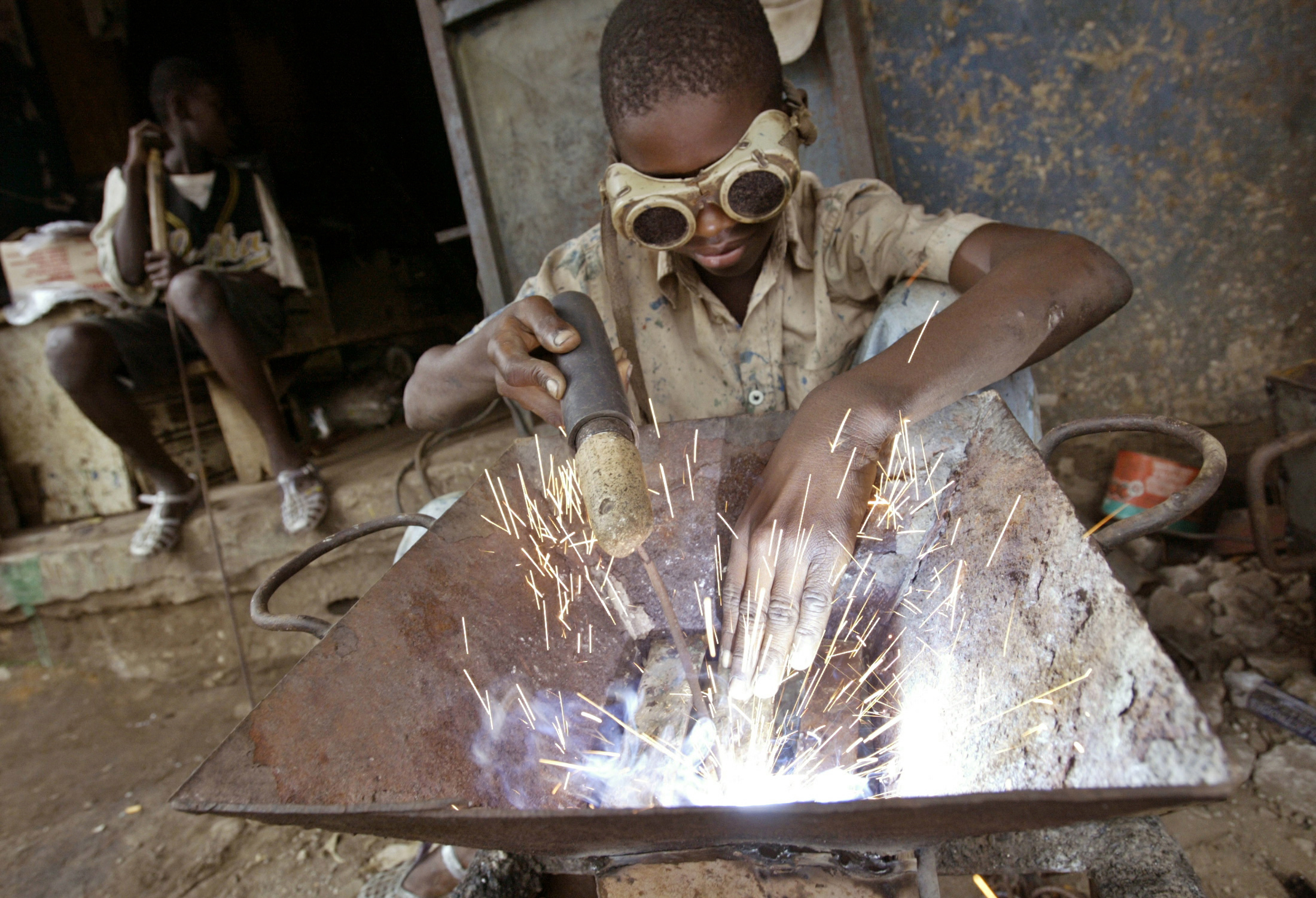 An Ivorian child welds in a wrought iron workshop in Abidjan June 15, 2005. Child labour is still pr..