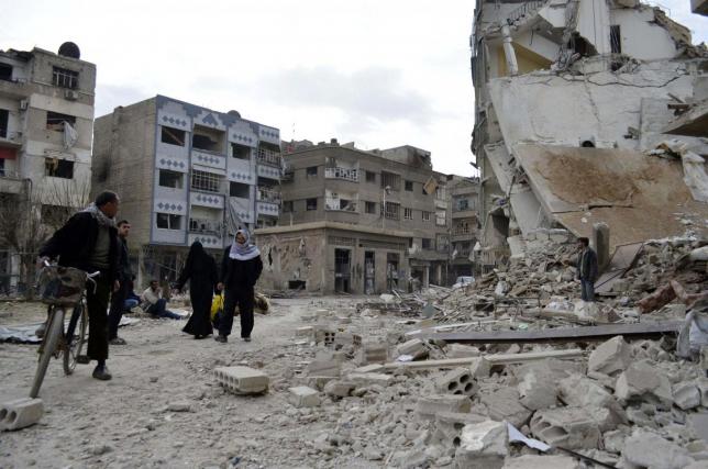 Residents walk past damaged buildings after what activists said were air strikes by forces loyal to Syria's President Bashar al-Assad in the Douma neighborhood of Damascus