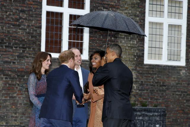 U.S. President Barack Obama holds an umbrella as he and first lady Michelle Obama are greeted by Britain's Prince William, his wife Catherine, Duchess of Cambridge, and Prince Harry, upon arrival for dinner at Kensington Palace in London, Britain