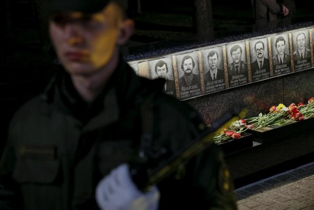 A serviceman stands guard in front of a memorial, dedicated to firefighters and workers who died from the Chernobyl nuclear disaster, during a night service in the city of Slavutych
