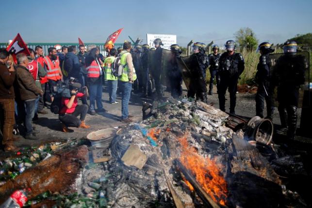Striking French labour union employees stand in front of a line of French police during an operation to free up a fuel depot near the Donges oil refinery