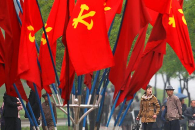 People walk behind party flags placed near April 25 House of Culture, the venue of Workers' Party of Korea (WPK) congress in Pyongyang