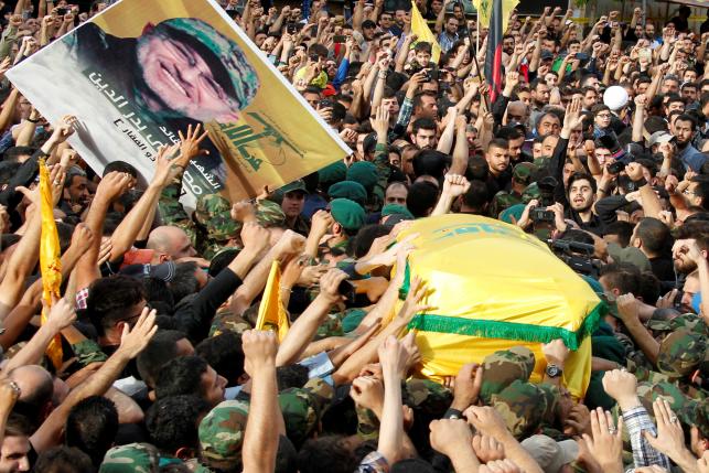 Hezbollah members carry the coffin and a picture of top Hezbollah commander Mustafa Badreddine, who was killed in an attack in Syria, during his funeral in Beirut's southern suburbs