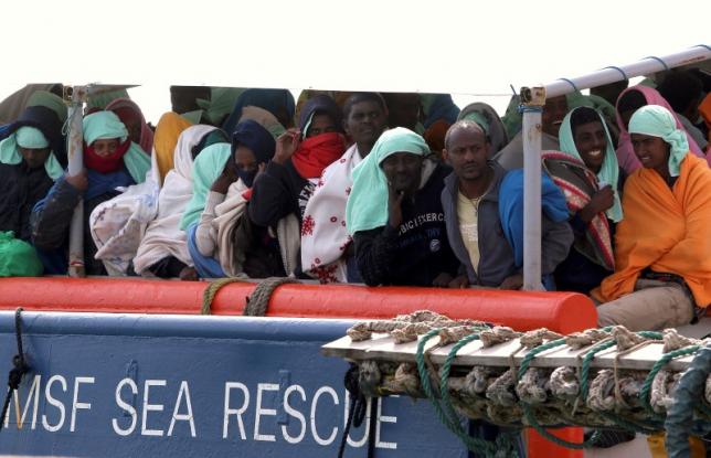 Migrants wait to disembark from the Medecins Sans Frontieres vessel at Pozzallo's harbour