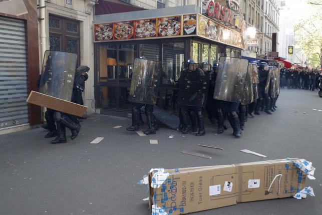 French riot police use their shields for protection against debris thrown by youths who protest against the French labour law proposal during the May Day labour union march in Paris