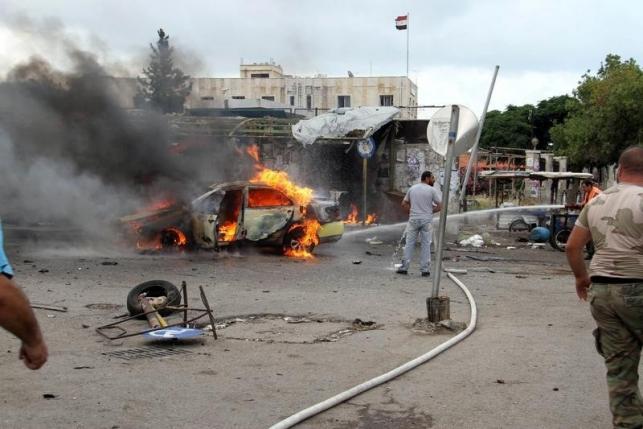 A firefighter tries to put out a fire from a burning car after explosions hit the Syrian city of Tartous