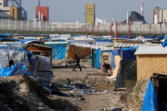 A migrant walks past makeshift shelters in the northern area on the final day of the dismantlement of the southern part of the camp called the 'Jungle" in Calais