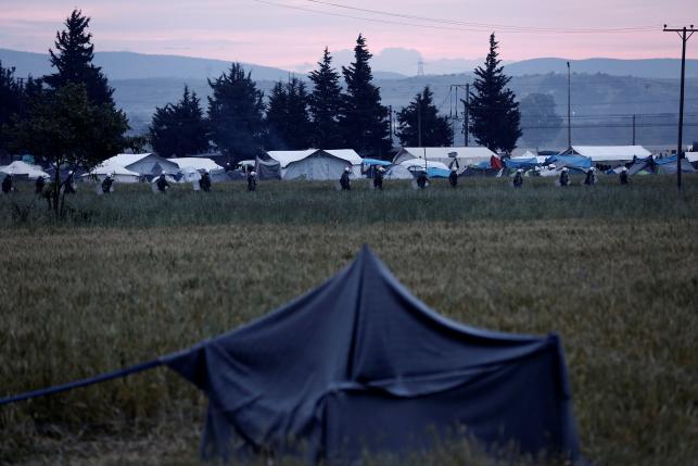Riot policemen walk amidst tents during a police operation at a refugee camp at the border between Greece and Macedonia, near the village of Idomeni