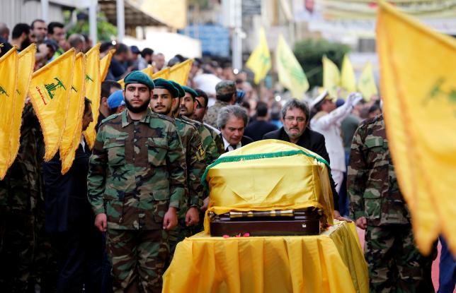 Brothers of top Hezbollah commander Mustafa Badreddine, who was killed in an attack in Syria, mourn over his coffin during his funeral in Beirut's southern suburbs
