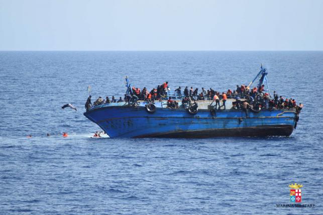 Migrants are seen on a capsizing boat before a rescue operation by Italian navy ships "Bettica" and "Bergamini" (unseen) off the coast of Libya