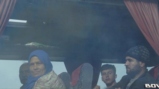Refugees and migrants are transferred on a bus to government camps, during a police operation to evacuate a makeshift camp near the village of Idomeni