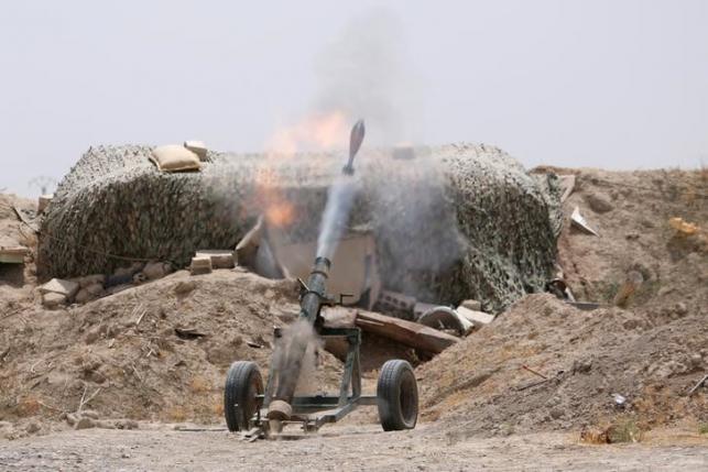 Fighters of the Syria Democratic Forces fire a mortar shell towards positions held by Islamic State fighters in northern province of Raqqa