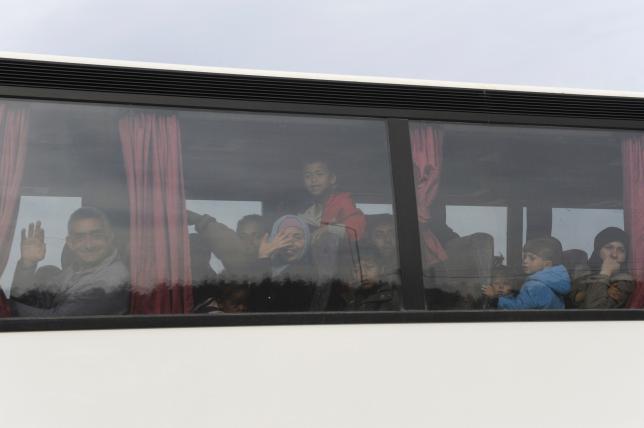 Refugees and migrants are transferred on a bus to government camps, during a police operation to evacuate a makeshift camp near the village of Idomeni