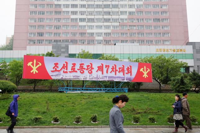 People walk in front of a banner announcing Workers' Party of Korea (WPK) congress placed near April 25 House of Culture, the venue of the congress in Pyongyang