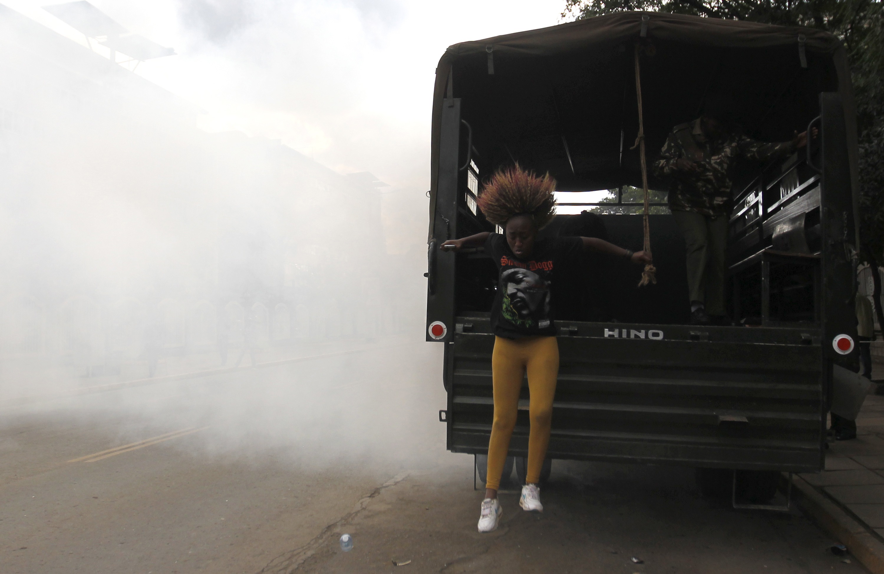 A detained protester jumps from a police truck as she escapes after riot police released teargas to disperse the #OccupyHarambeeAve demonstration in Nairobi