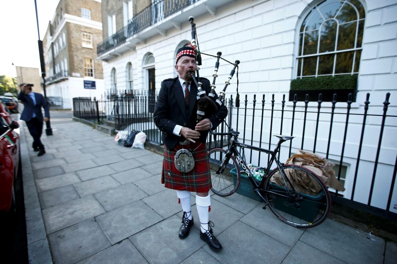 A lone piper plays his bagpipes outside the home of former London Mayor Boris Johnson