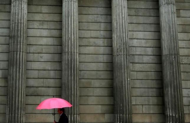 A man holding an umbrella walks past the Bank of England in the City of London