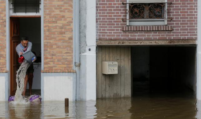 A man scoops water from his house in the flooded suburb of Villeneuve-Trillage in Villeneuve Saint-Georges