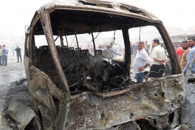 People inspect the site of car bomb attack in Baghdad al-Jadeeda