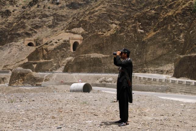 A member of Pakistan's Frontier Corps uses binoculars to survery the border region outside Torkham