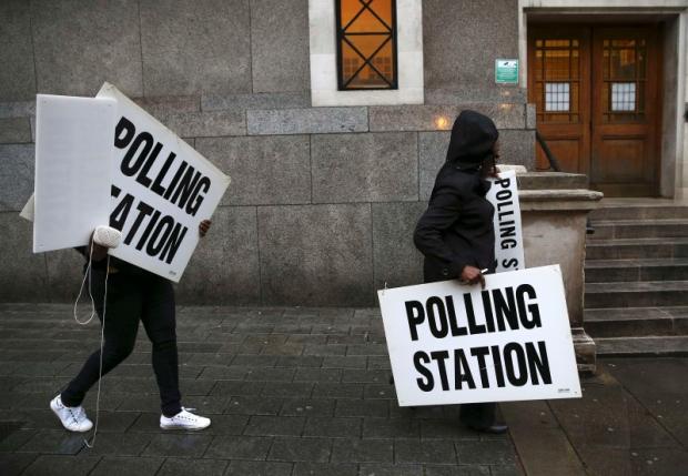 Electoral workers carry signs as they prepare a polling station for the Referendum on the European Union in north London